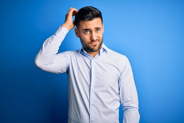Young handsome man wearing elegant shirt standing over isolated blue background confuse and wonder...