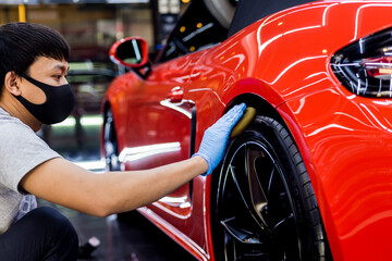 Car service worker polishing car wheels with microfiber cloth.