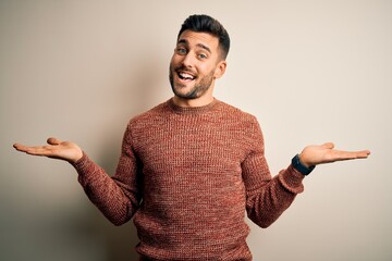 Young handsome man wearing casual sweater standing over isolated white background smiling showing...
