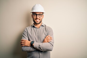 Young architect man wearing builder safety helmet over isolated background happy face smiling with...