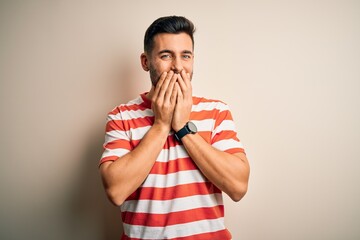 Young handsome man wearing casual striped t-shirt standing over isolated white background laughing...