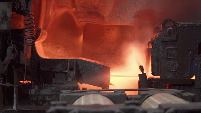 The hot sheet of metal moves on the conveyor. Slow motion.