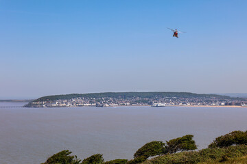 Fototapeta na wymiar Coastguard Helicopter flying in the blue sky over the bay of Weston Super Mare in Somerset, UK