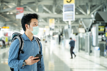 Asian traveler man wearing face mask in departure terminal in airport.