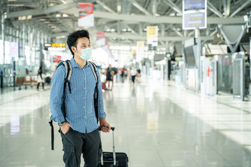 Asian traveler man wearing face mask in departure terminal in airport.