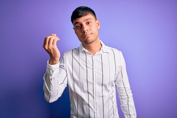 Naklejka premium Young handsome hispanic man wearing elegant business shirt standing over purple background Doing Italian gesture with hand and fingers confident expression