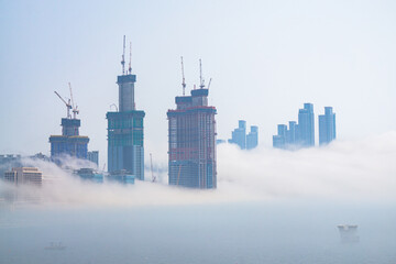 Thick large and heavy mist blow from the sea to the land and pass through skyscrapers and cover all other buildings in the area
