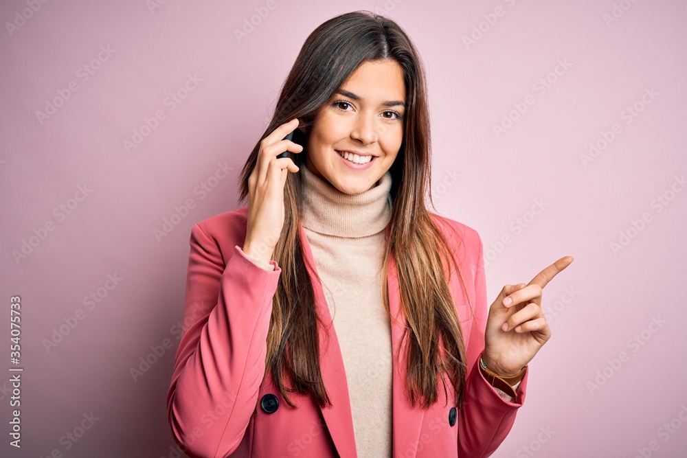 Poster Young beautiful girl having conversation talking on the smartphone over white background very happy pointing with hand and finger to the side