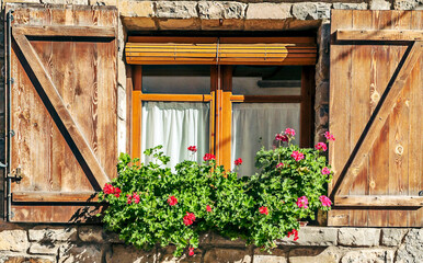 Fototapeta na wymiar Facade of ancient house decorated with flowers in the windows