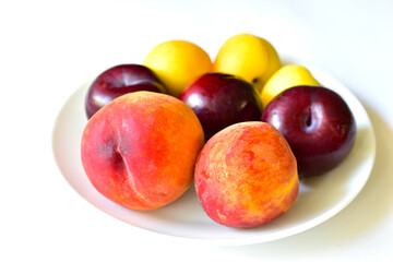 Ripe and juicy peaches and apricots on a white plate