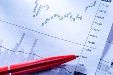 Red ballpoint pen lying on statistical graphs