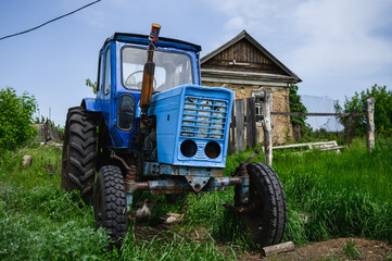 Blue old tractor. House in the village.