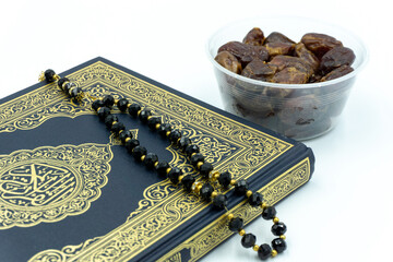 Holy Al Quran with written arabic calligraphy meaning of Al Quran with dates and rosary over white background