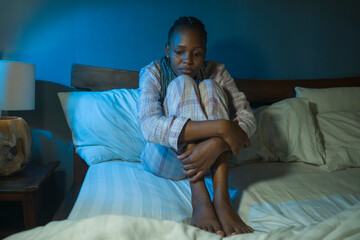 Obraz premium young sad and depressed black African American woman lying on bed at home unhappy and sleepless at night feeling overwhelmed suffering depression problem and insomnia