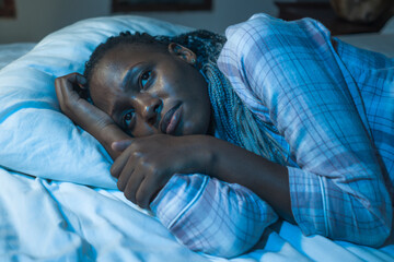 young sad and depressed black African American woman lying on bed at home unhappy and sleepless at...