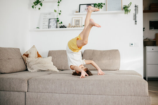 Beautiful Little Toddler Tumbling On Sofa At Home.