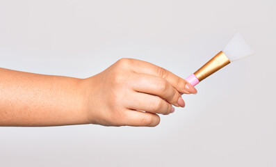 Hand of caucasian young woman holding eye brush over isolated white background