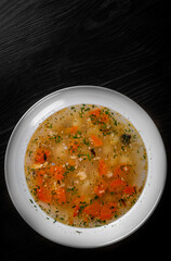 Fresh fish soup in white plate on black wooden table background