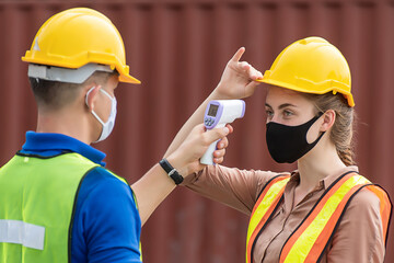 Workers with protective mask, Engineer worker waring surgical mask checking body temperature using infrared digital thermometer check temperature before into work place,
