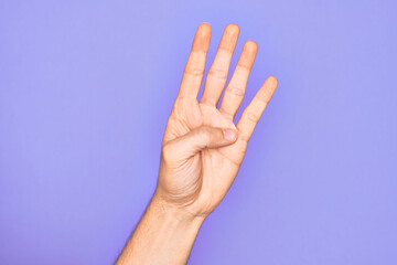 Hand of caucasian young man showing fingers over isolated purple background counting number 4 showing four fingers