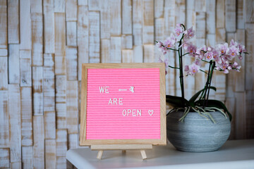 Reopening text on pink letter board near the keyboard. Business concept. Service, restaurant, shop and cafe re-opening. Reopening of the place after the quarantine due to covid-19. We are open again.