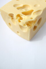 A piece of semi-hard cheese with holes on a white background. Close-up. Vertical photo. There is a place for text.
