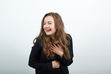 Obraz premium Young Attractive Woman Brunette In In Black T-Shirt And Sweater On White Background, Happy Female Smiling, Laughing, Holding Hand To Her Stomach. Joy Of The People In A Good Mood
