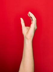 Beautiful hand of man showing fingers raised up doing catch gesture over isolated red background