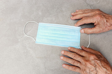 senior man's hands holding healthcare face mask, protect Covid-19