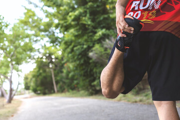 Fototapeta premium sportsman runner warm up his body before start running on road in the park with soft-focus and over light in the background