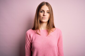 Young beautiful redhead woman wearing casual sweater over isolated pink background Relaxed with serious expression on face. Simple and natural looking at the camera.