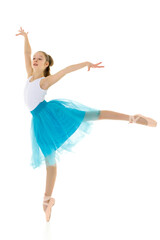 Cute little girl in a tutu and pointe shoes dancing in the studio on a white background.