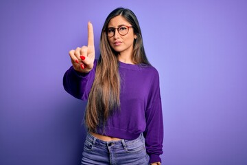 Young beautiful smart woman wearing glasses over purple isolated background Pointing with finger up and angry expression, showing no gesture