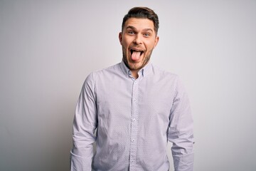 Young business man with blue eyes standing over isolated background sticking tongue out happy with funny expression. Emotion concept.