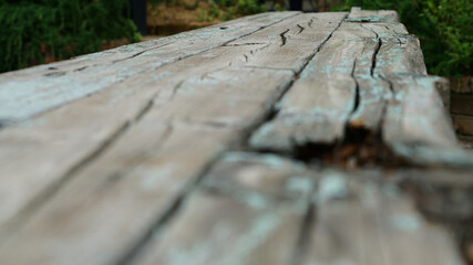a wooden bench in which paint is peeling and rotting with age.