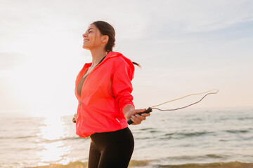young attractive woman doing sport exercises in morning sunrise on sea beach in sports wear,...
