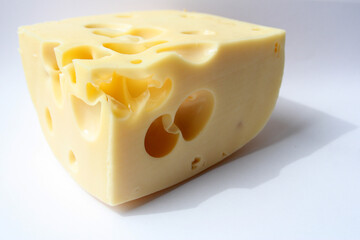 A piece of cheese with large holes on white. Maasdam cheese close-up. Copy space. 
