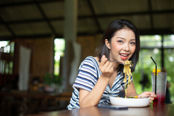 Woman eating delicious pasta in restaurant
