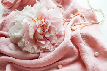 romantic composition. pink peonies on a background of pink silk and pearls