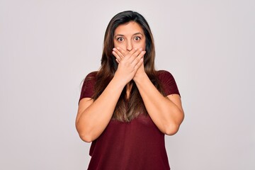 Young hispanic woman wearing casual t-shirt standing over isolated background shocked covering mouth with hands for mistake. Secret concept.