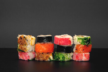 Pile of multiple hosomaki sushi on black background