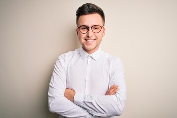 Obraz premium Young handsome business mas wearing glasses and elegant shirt over isolated background happy face smiling with crossed arms looking at the camera. Positive person.