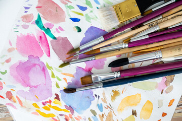Multiple painting brushes on colorful watercolor background