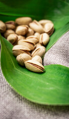 Pistachio nuts on a green tropical leaf. Tropical background, walnut.