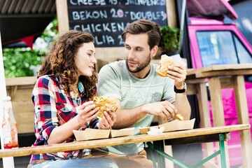 Portrait of young attractive couple eating ham burger
