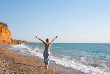 Fototapeta na wymiar happy woman walks barefoot on the sand by the sea