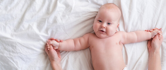 Banner. Adorable smiling baby boy on white blanket in bedroom. Newborn child relaxing in bed. Family morning at home. Copyspace.