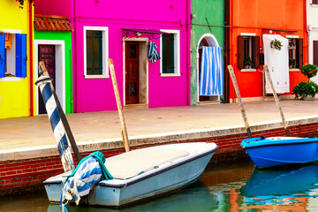 Fototapeta na wymiar Colorful houses in Burano near Venice, Italy with boats. Famous tourist attraction in Venice.