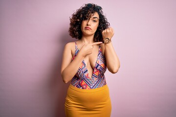 Young beautiful arab woman on vacation wearing swimsuit and sunglasses over pink background In...
