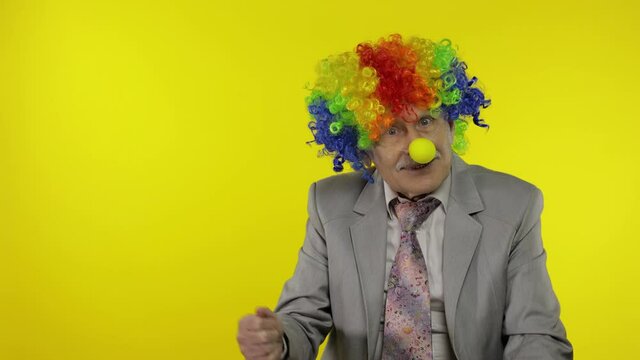 Elderly clown businessman entrepreneur boss pointing at something. Copy space